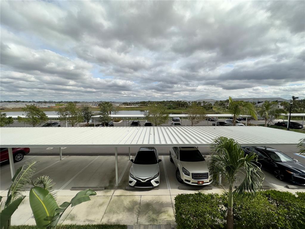 A view from an elevated balcony overlooking a covered parking area and a lake — 14091 HERITAGE LANDING BOULEVARD UNIT 127, PUNTA GORDA, FL