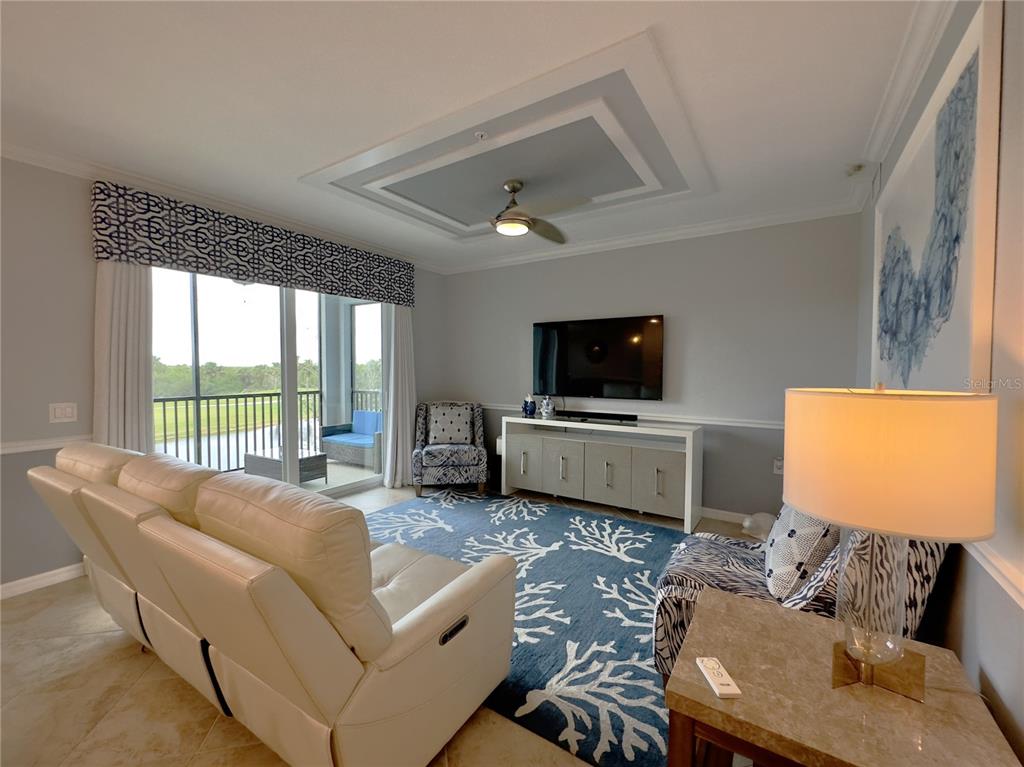 A living room features a white leather sofa, a coral-patterned rug, and a balcony view — 14091 HERITAGE LANDING BOULEVARD UNIT 127, PUNTA GORDA, FL