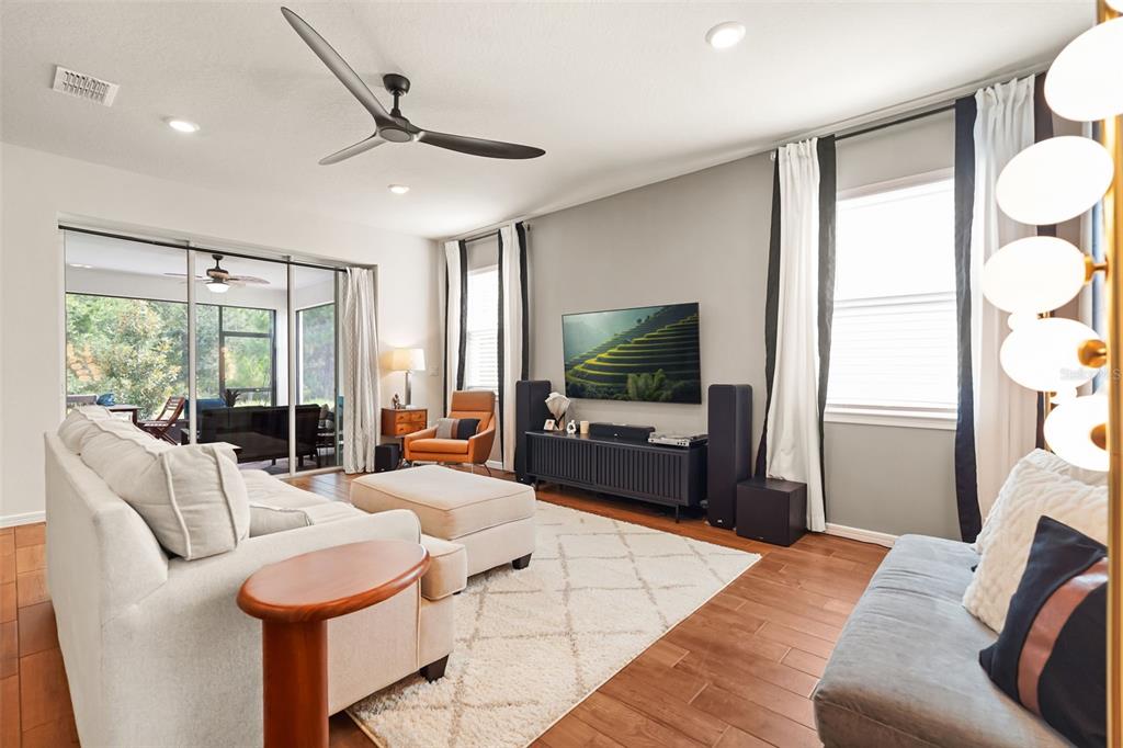 A living room features a white sofa, a television, and a sliding door to a patio — 17446 SAW PALMETTO AVENUE, CLERMONT, FL