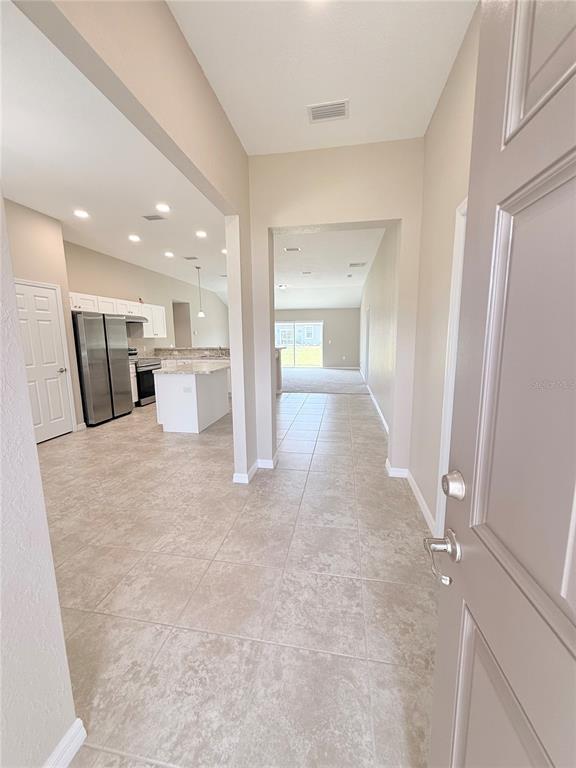 A view from an open doorway into a tiled entryway, kitchen, and living area — 15712 SW 37TH CIRCLE, OCALA, FL