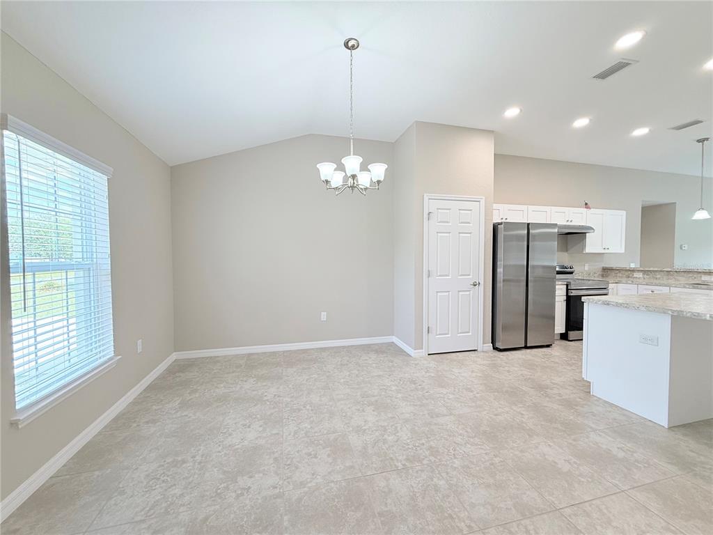 A dining area with tile flooring, a chandelier, and an adjacent kitchen with stainless appliances — 15712 SW 37TH CIRCLE, OCALA, FL
