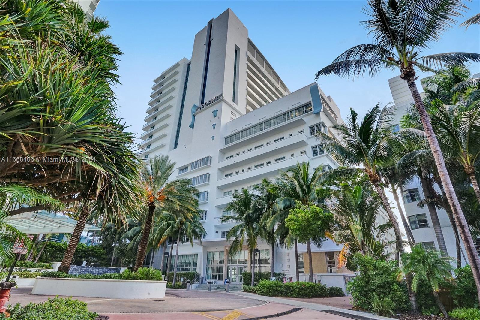 A tall white modern high-rise building is surrounded by lush palm trees and tropical landscaping — 4391 Collins Ave, Miami Beach FL 33140, MIAMI BEACH, FL