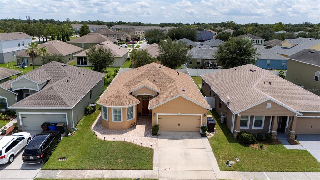 An aerial view shows a tan suburban house with a shingled roof and driveway — 1831 CENTENNIAL AVENUE, ST CLOUD, FL