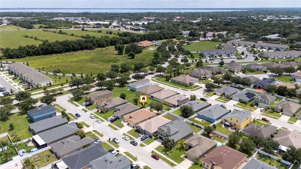 An aerial view shows a suburban neighborhood with houses, streets, and surrounding green space — 1831 CENTENNIAL AVENUE, ST CLOUD, FL