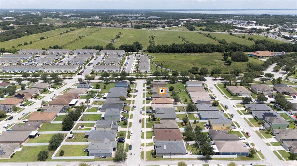 An aerial view shows a suburban neighborhood with rows of houses and a large field — 1831 CENTENNIAL AVENUE, ST CLOUD, FL