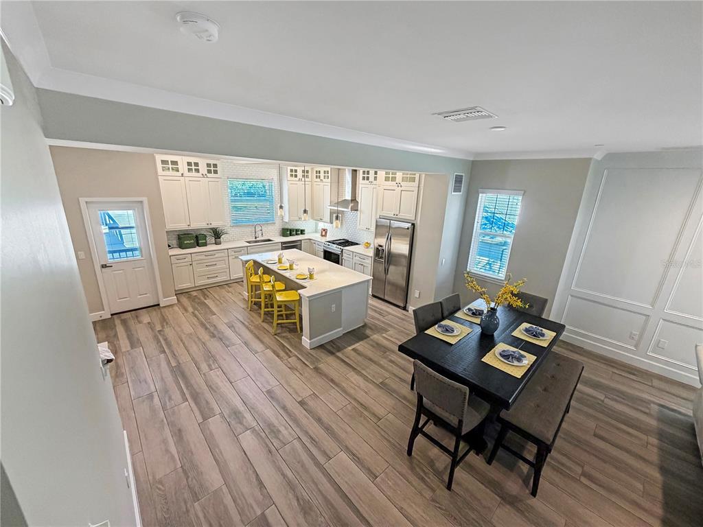 An open-concept kitchen and dining area featuring white cabinetry, a central island, and wood-look flooring — 461 GERANIUM PARK WAY, WINTER GARDEN, FL