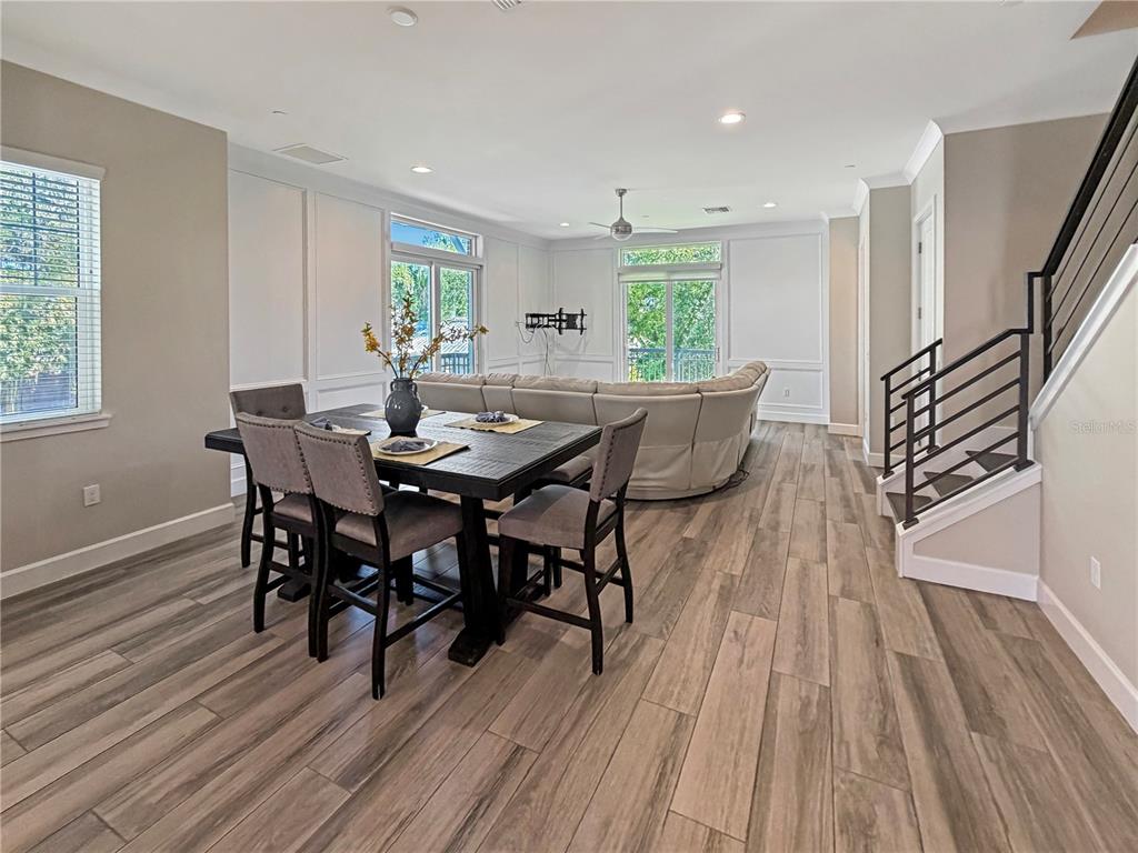 A dining area with a dark wood table and chairs sits before a living room — 461 GERANIUM PARK WAY, WINTER GARDEN, FL