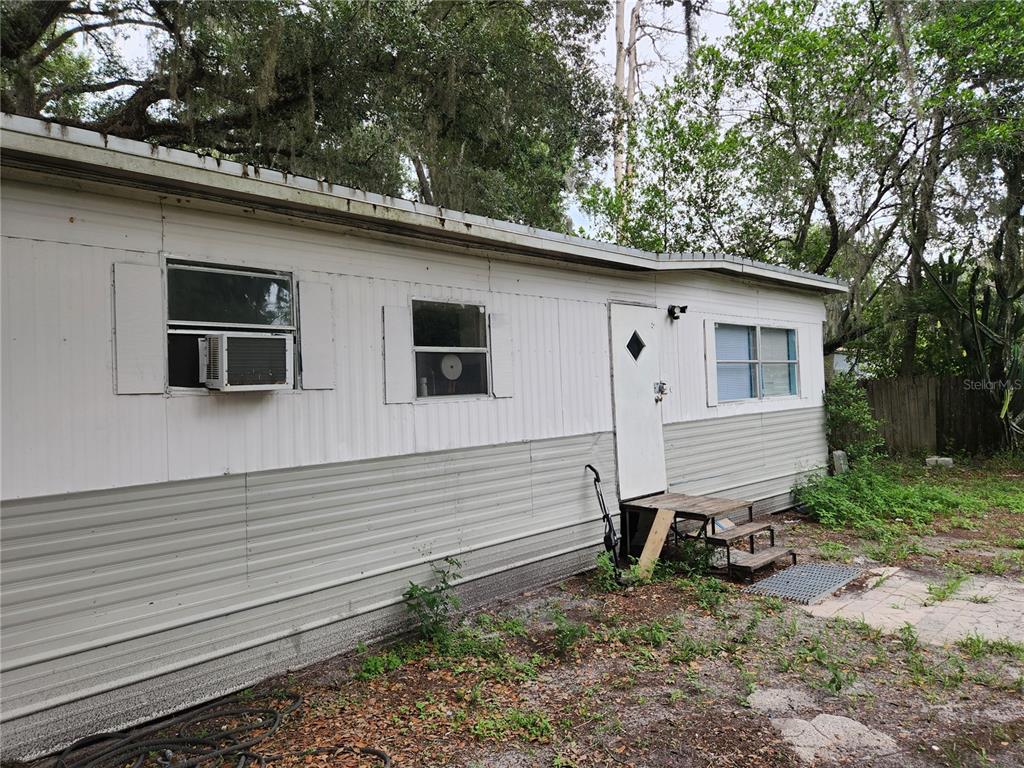 The exterior of a single-wide mobile home features white and gray siding with window units — 24815 AUDREY ROAD, LAND O LAKES, FL