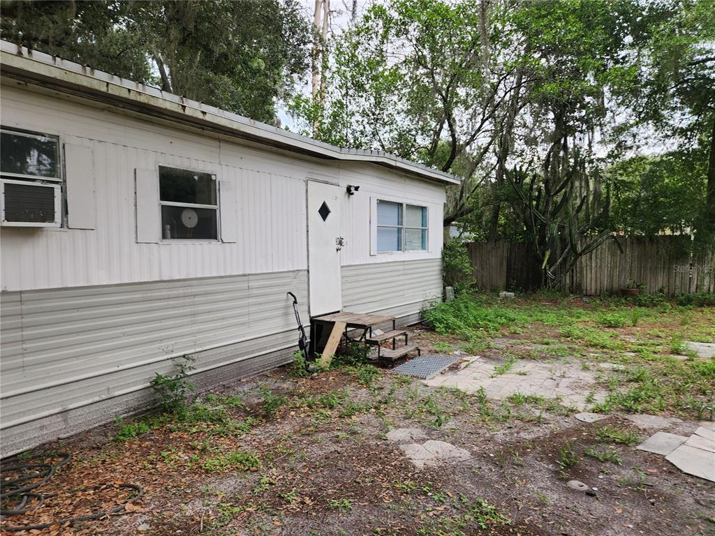 The exterior of a white mobile home features a small wooden staircase and a window unit — 24815 AUDREY ROAD, LAND O LAKES, FL