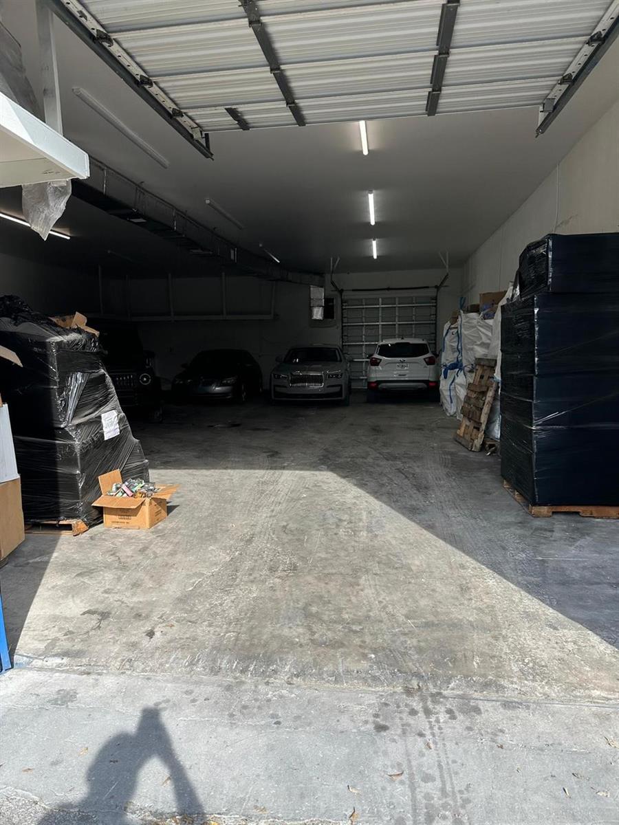 A large, industrial-style garage space contains several parked cars and stacks of wrapped inventory — 3300 Burris Road, Davie FL 33314, DAVIE, FL