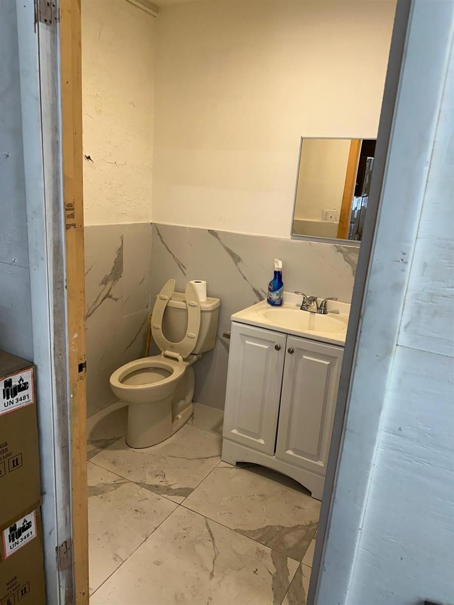A small bathroom features a white vanity, a beige toilet, and gray marble-look tile flooring — 3300 Burris Road, Davie FL 33314, DAVIE, FL