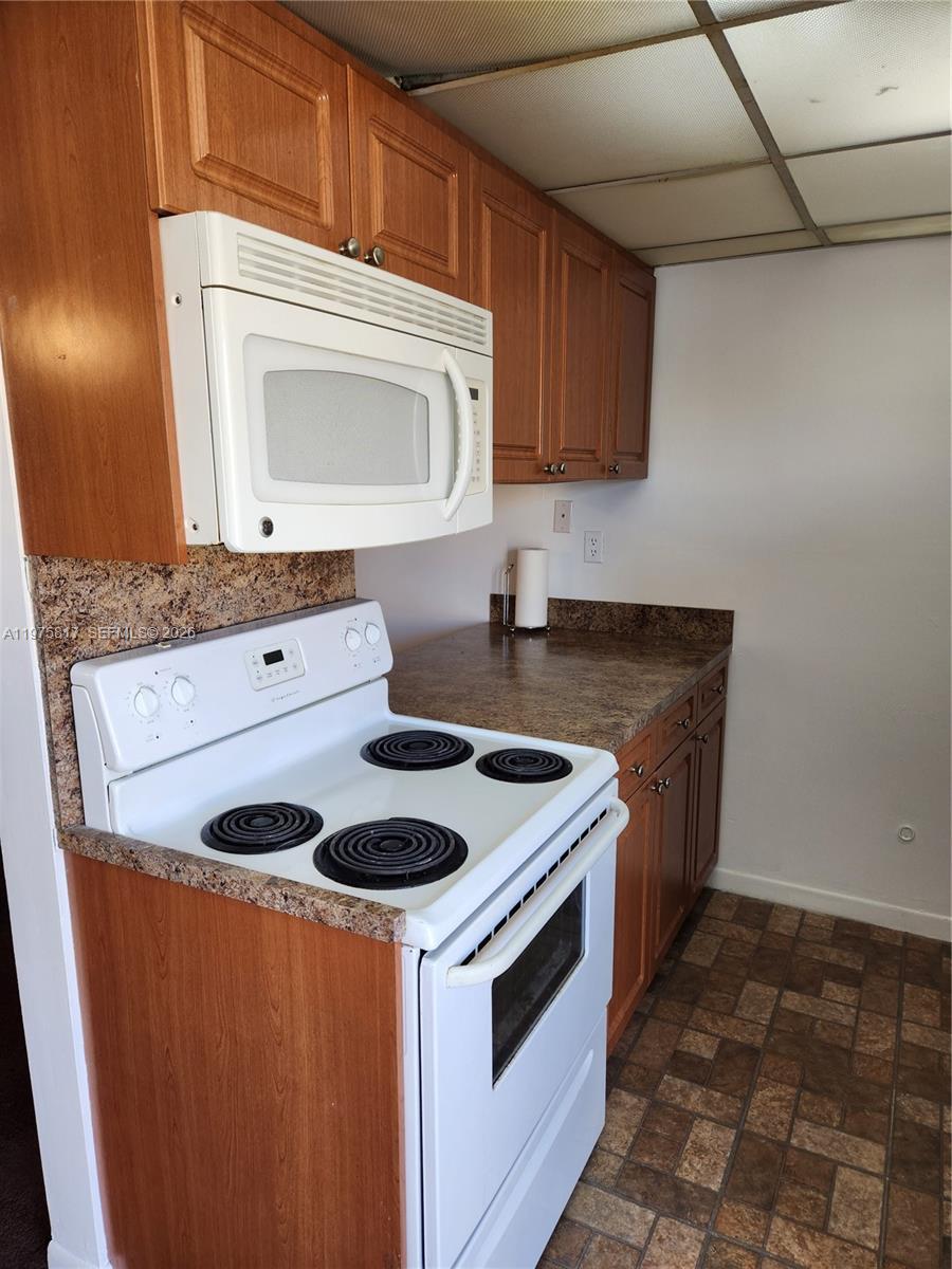 A kitchen features wood cabinets, a white electric stove, a microwave, and brown countertops — 777 SW 9th Ave # 301, Miami FL 33130, MIAMI, FL