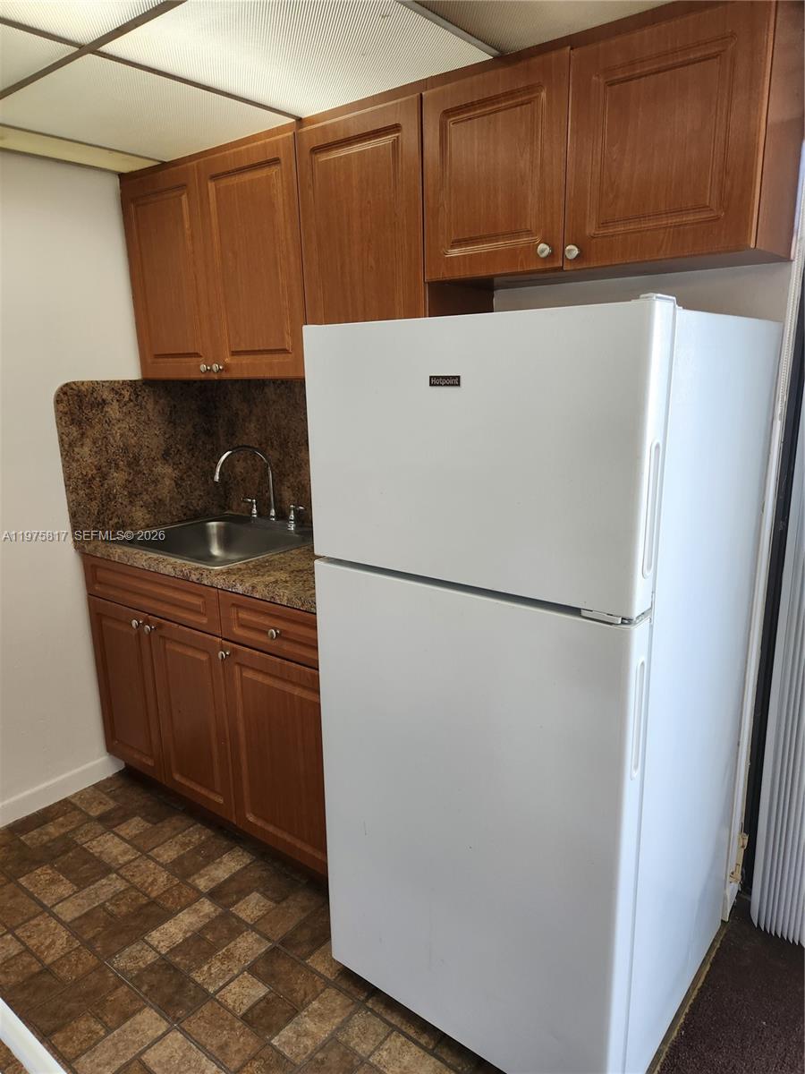 A small kitchen features wooden cabinets, a white refrigerator, and a brown speckled countertop — 777 SW 9th Ave # 301, Miami FL 33130, MIAMI, FL