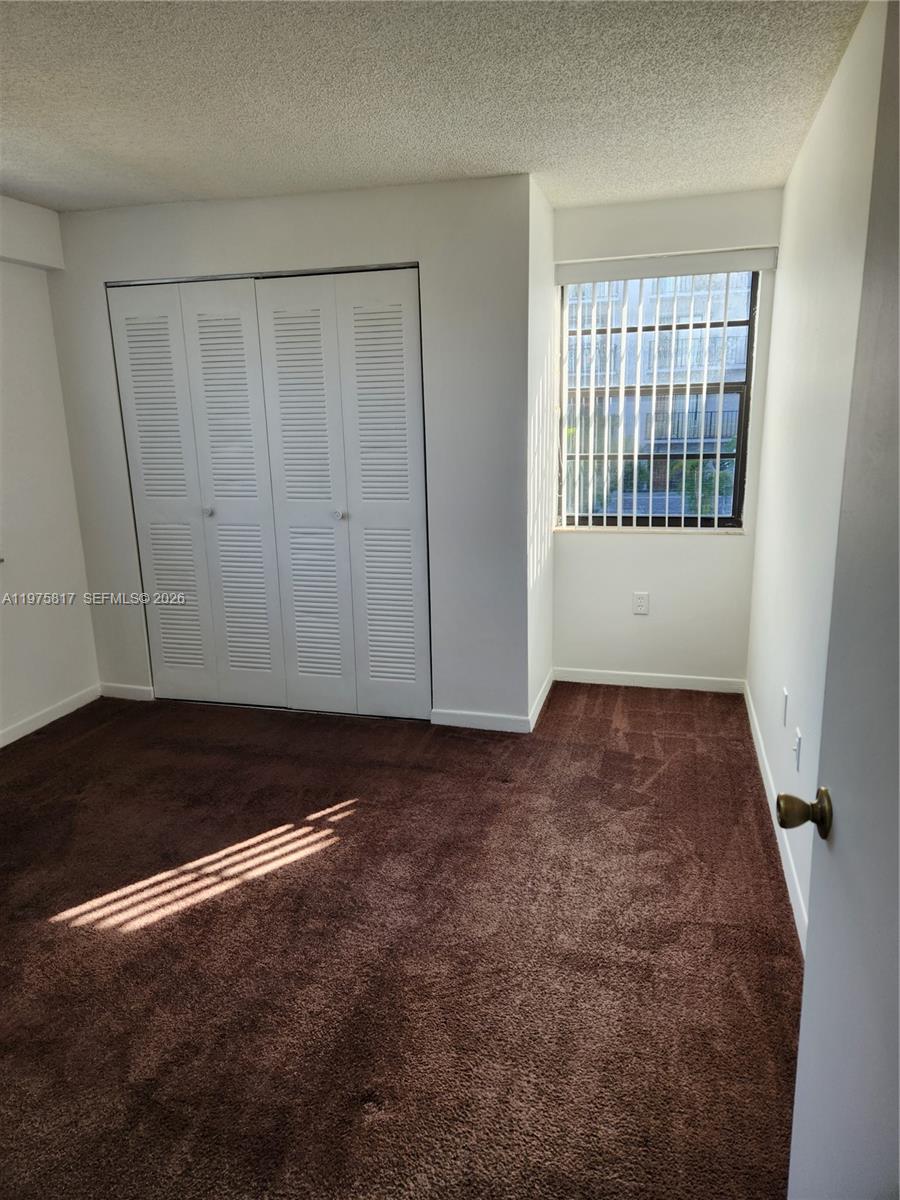 A bedroom features brown carpeting, white walls, a louvered closet, and a window with blinds — 777 SW 9th Ave # 301, Miami FL 33130, MIAMI, FL