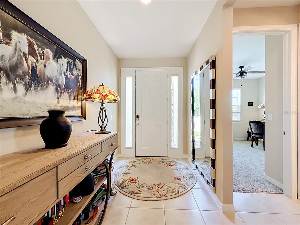 A foyer features a wooden console table, a round rug, and a large wall mirror — 25224 LAHORE LANE, PUNTA GORDA, FL