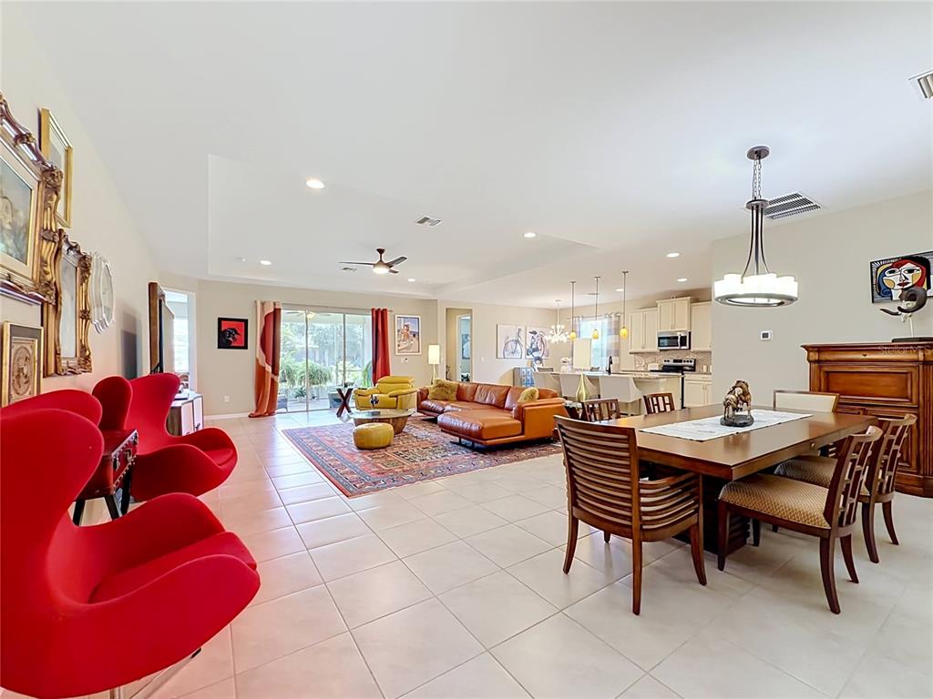 A living room with a leather sectional, patterned rug, and an open kitchen with island seating — 25224 LAHORE LANE, PUNTA GORDA, FL