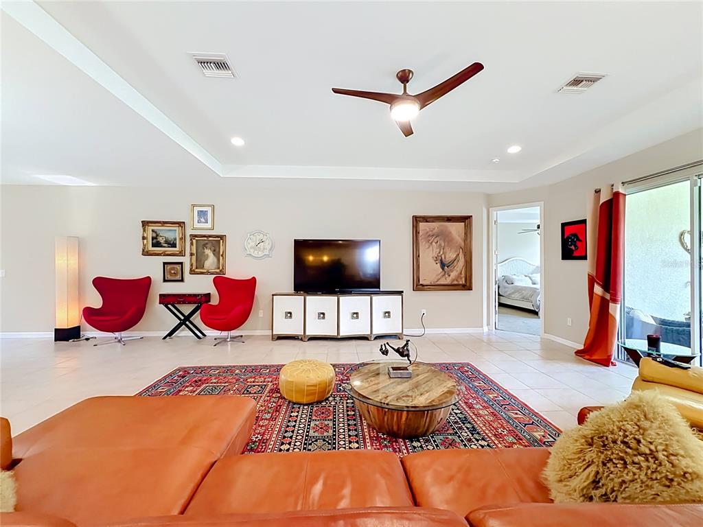 An open-concept living and dining area features tile floors, a leather sofa, and red chairs — 25224 LAHORE LANE, PUNTA GORDA, FL