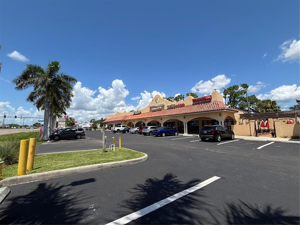 A strip mall with a parking lot, palm tree, and blue sky in the background — 2672-2686 TAMIAMI TRAIL UNIT 6B,7B, PORT CHARLOTTE, FL