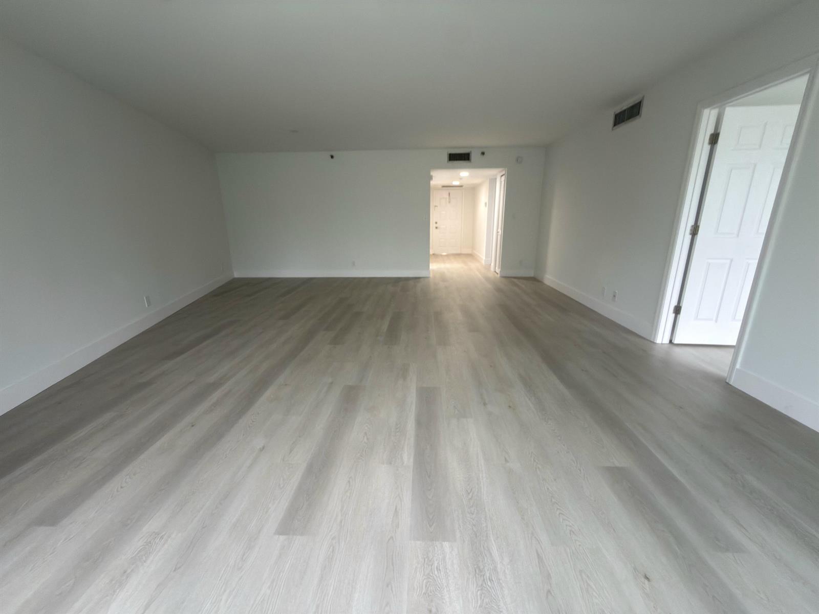 An empty room with white walls and light-colored wood-look flooring features an open doorway — 625 Oaks Drive # 305, Pompano Beach FL 33069, POMPANO BEACH, FL