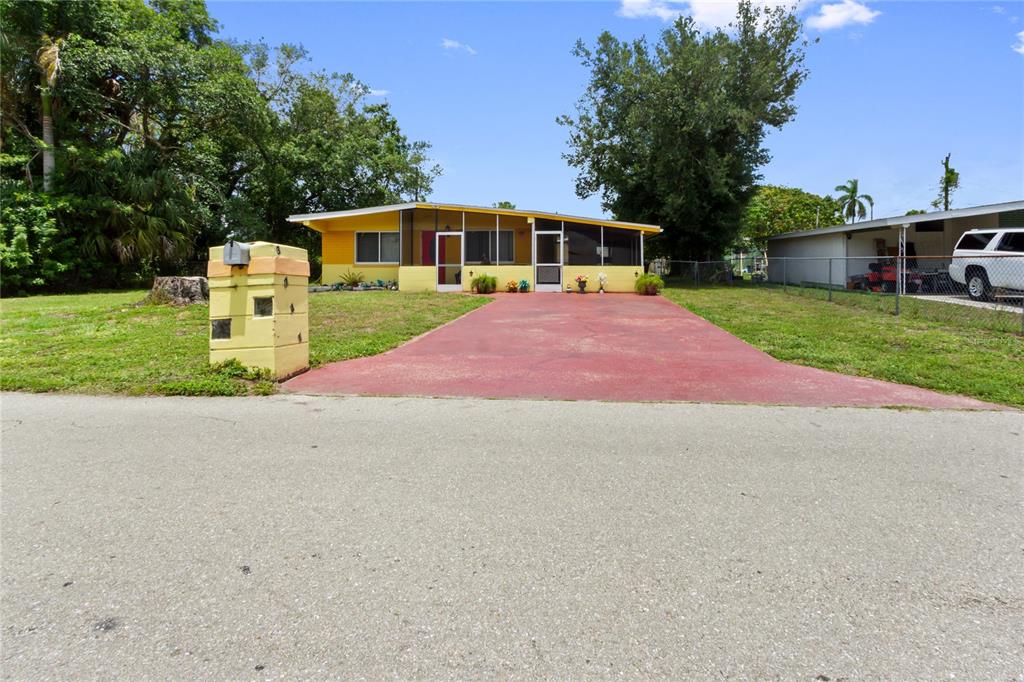A yellow single-story house with a screened front porch and a red concrete driveway — 3741 BELL STREET, FORT MYERS, FL
