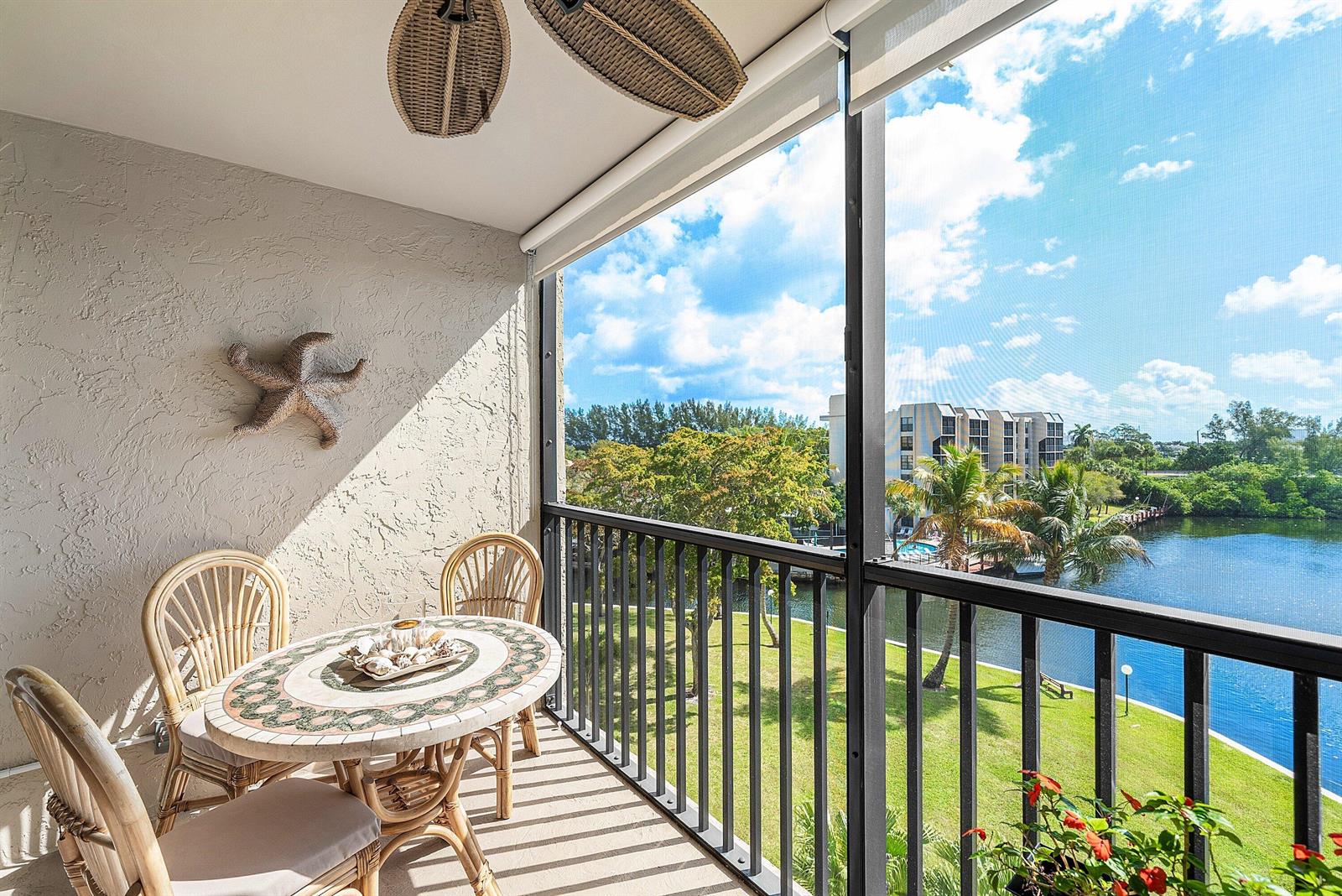 A screened balcony features a round tiled table, wicker chairs, and a waterfront view — 7 Royal Palm Way # 507, Boca Raton FL 33432, BOCA RATON, FL