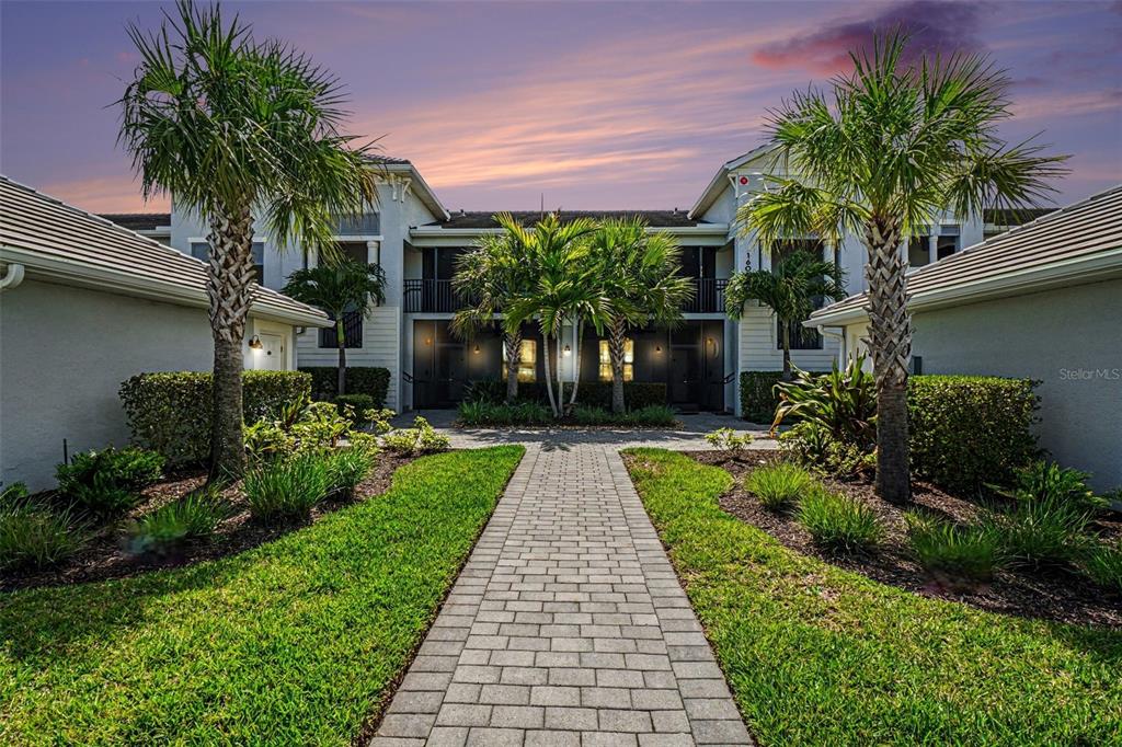 A paved walkway leads to the entrance of a two-story building with palm trees — 16000 GRASSLAND LANE UNIT 3112, PUNTA GORDA, FL