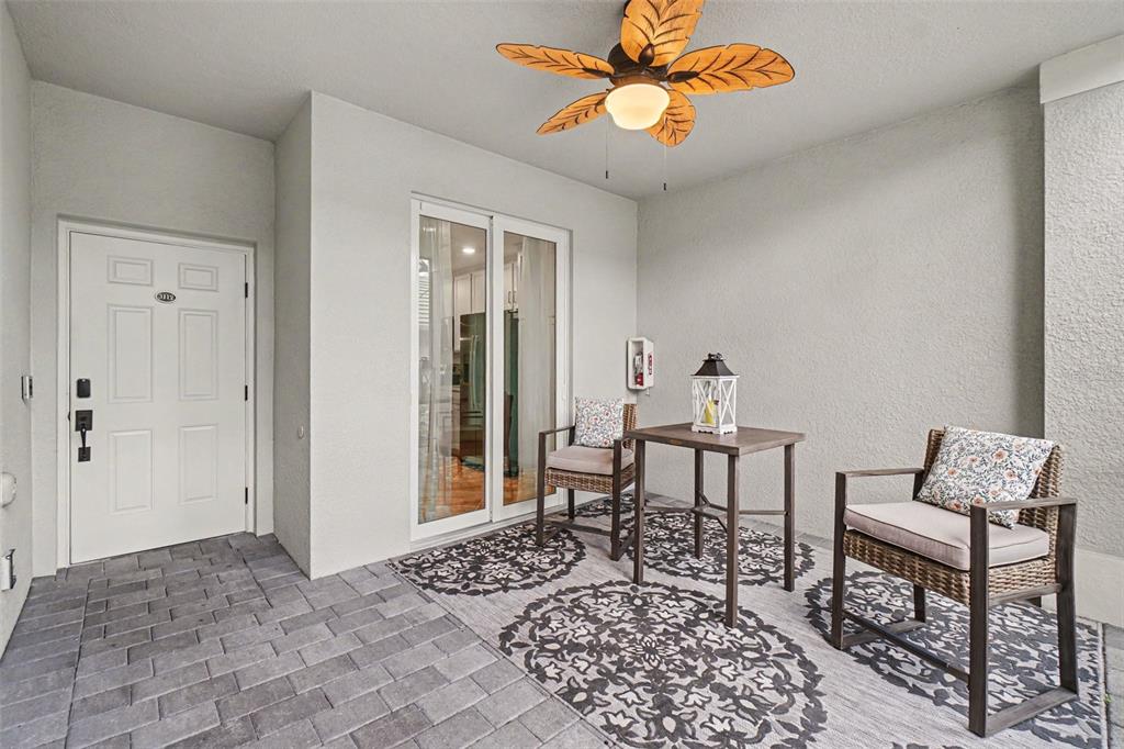 A covered patio features a ceiling fan, two wicker chairs, a small table, and pavers — 16000 GRASSLAND LANE UNIT 3112, PUNTA GORDA, FL