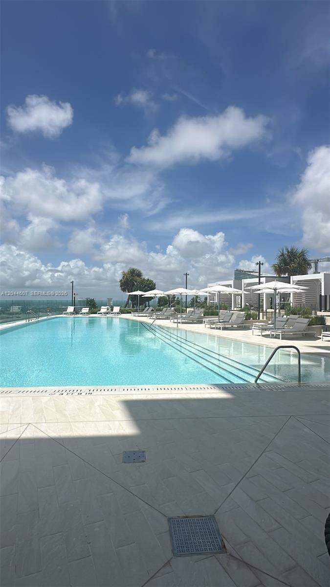 An outdoor swimming pool with lounge chairs and umbrellas under a blue sky — 300 Biscayne Blvd Way # 1909, Miami FL 33131, MIAMI, FL