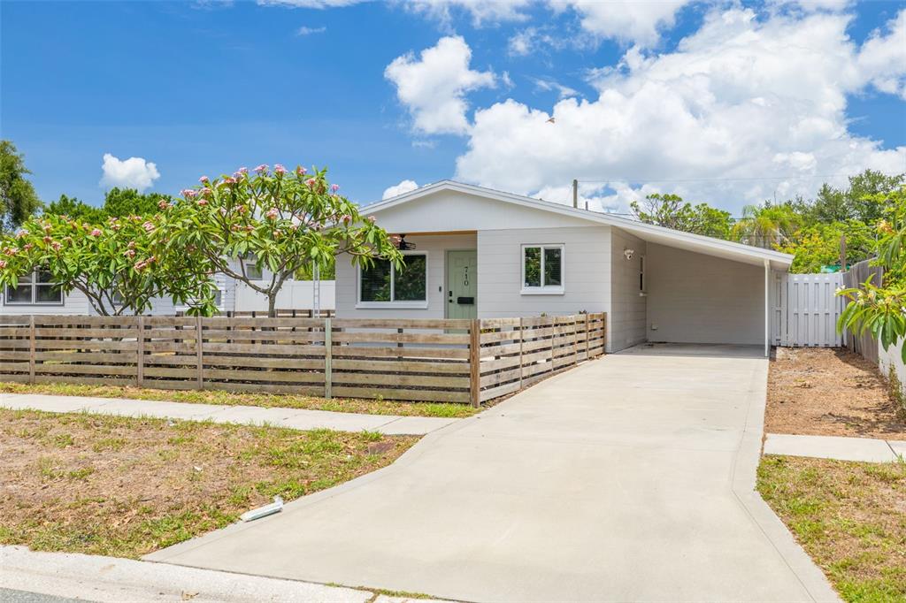 A single-story house with a light gray exterior, a wooden fence, and a concrete driveway — 710 50TH AVENUE N, ST PETERSBURG, FL
