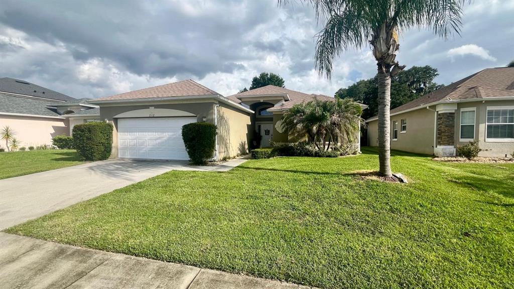 A single-story house with a white garage door, a palm tree, and a grassy lawn — 2112 BUNKER VIEW COURT, KISSIMMEE, FL