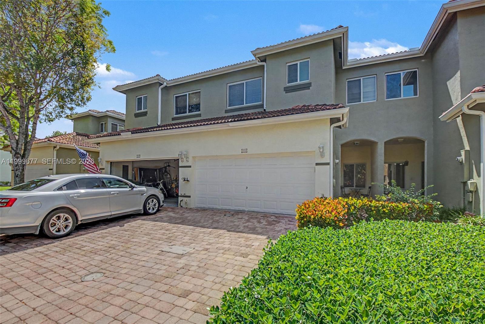 A two-story townhouse with a paved driveway, a two-car garage, and a manicured hedge — 2020 SE 23rd Ave, Homestead FL 33035, HOMESTEAD, FL