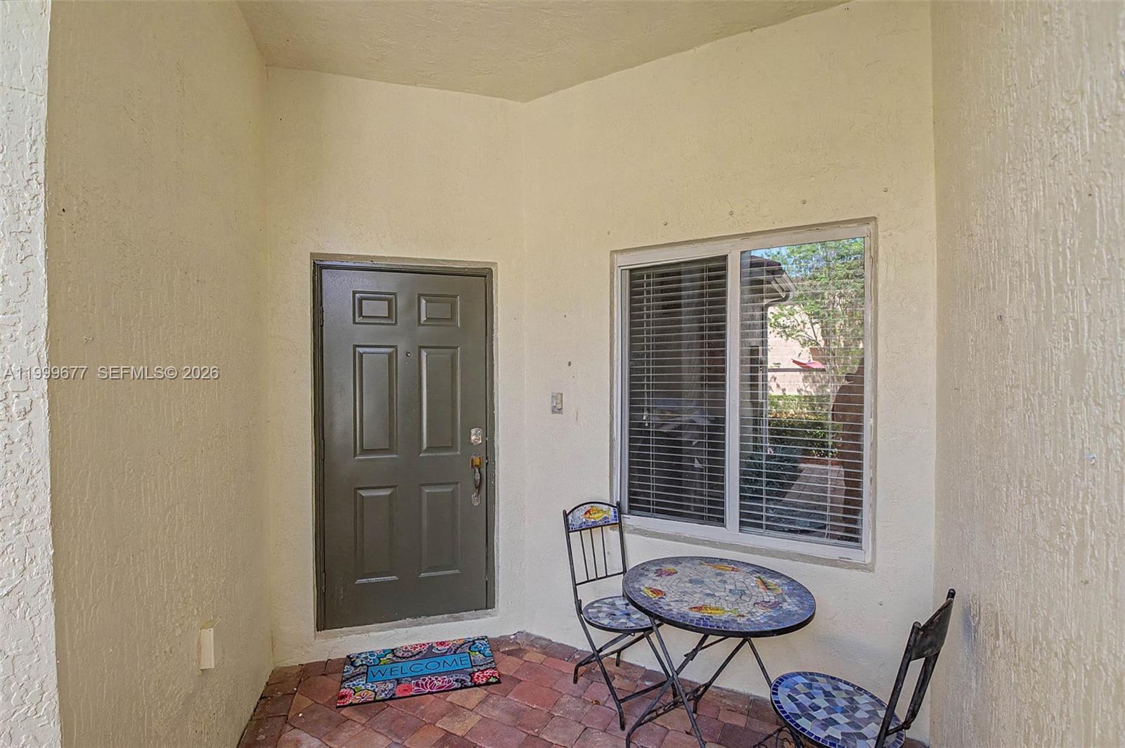 A small patio features a brick floor, a dark door, a window, and bistro furniture — 2020 SE 23rd Ave, Homestead FL 33035, HOMESTEAD, FL