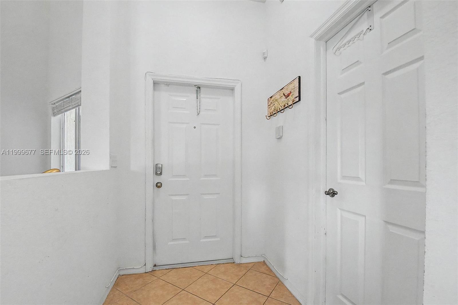 An entryway features a white front door, a side door, and tan tile flooring — 2020 SE 23rd Ave, Homestead FL 33035, HOMESTEAD, FL