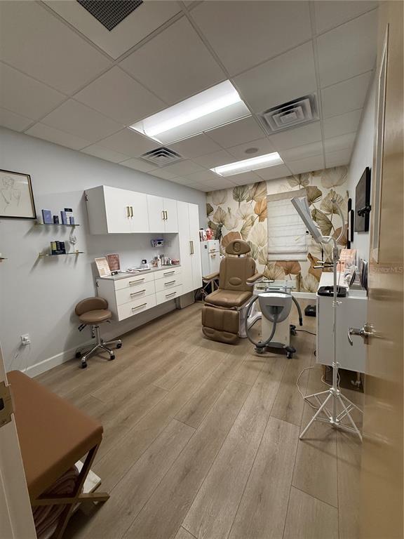 A treatment room features a medical chair, white cabinetry, wood-look flooring, and floral wallpaper — 2201 W SWANN AVENUE, TAMPA, FL