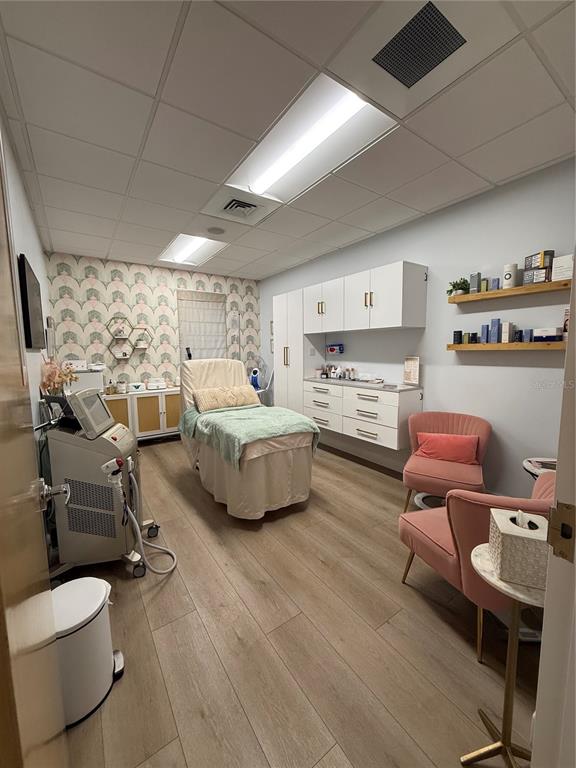 A treatment room features a massage table, pink chairs, white cabinetry, and wood-look flooring — 2201 W SWANN AVENUE, TAMPA, FL