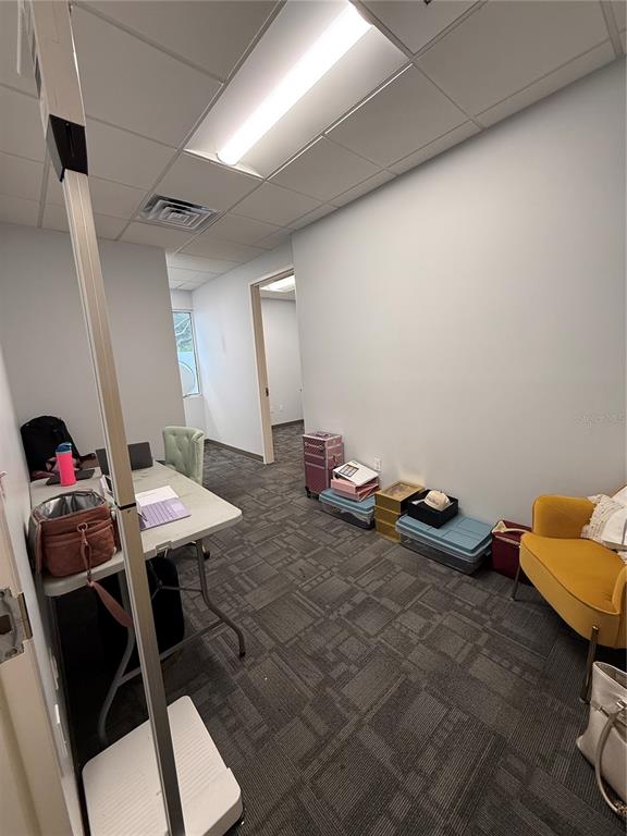 An office space features a folding table, a yellow armchair, and gray carpeted flooring — 2201 W SWANN AVENUE, TAMPA, FL