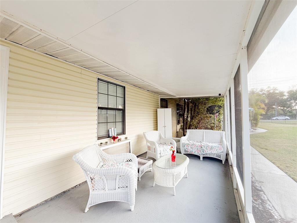 A screened-in porch features light yellow siding, white wicker furniture, and a concrete floor — 4219 E MICHIGAN STREET UNIT 4219, ORLANDO, FL