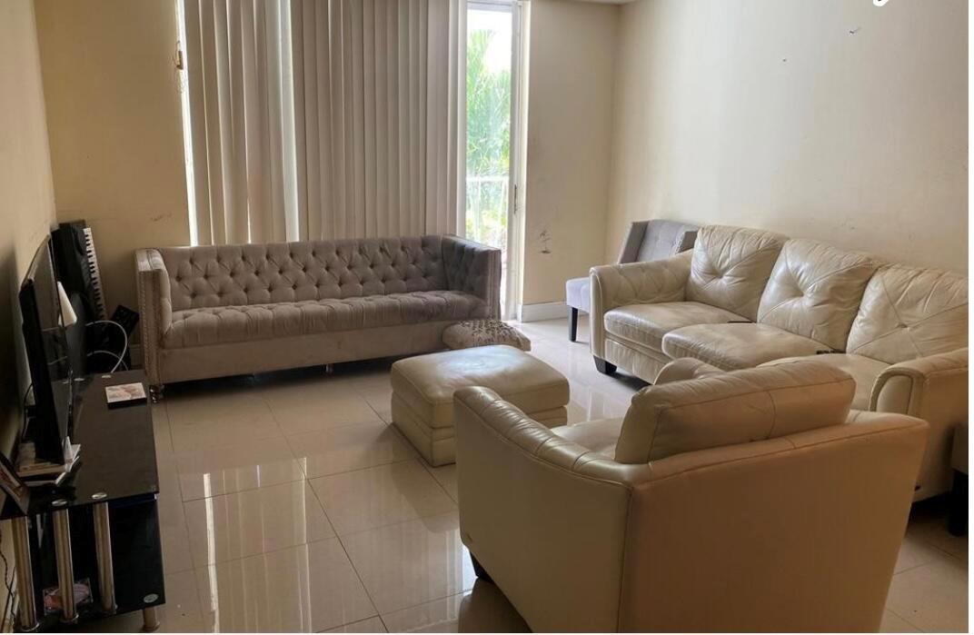 A living room features a tufted grey sofa, a white leather sectional, and tile flooring — 486 NW 165th St Road # 206, Miami FL 33169, MIAMI, FL