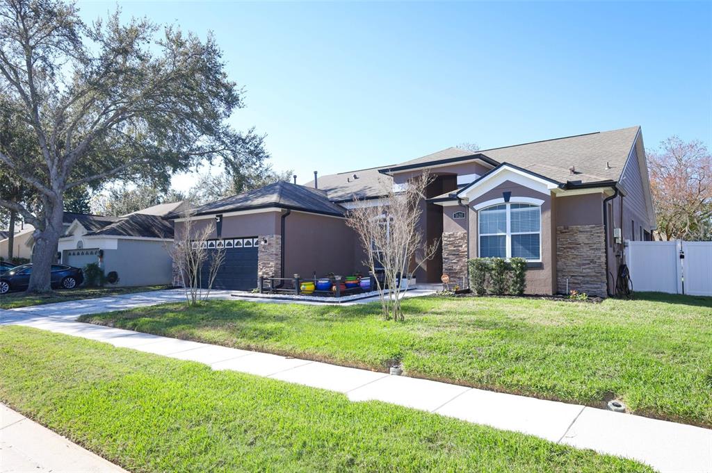 A single-story house with a brown exterior, stone accents, a dark garage, and a lawn — 1620 PARKGLEN CIRCLE, APOPKA, FL