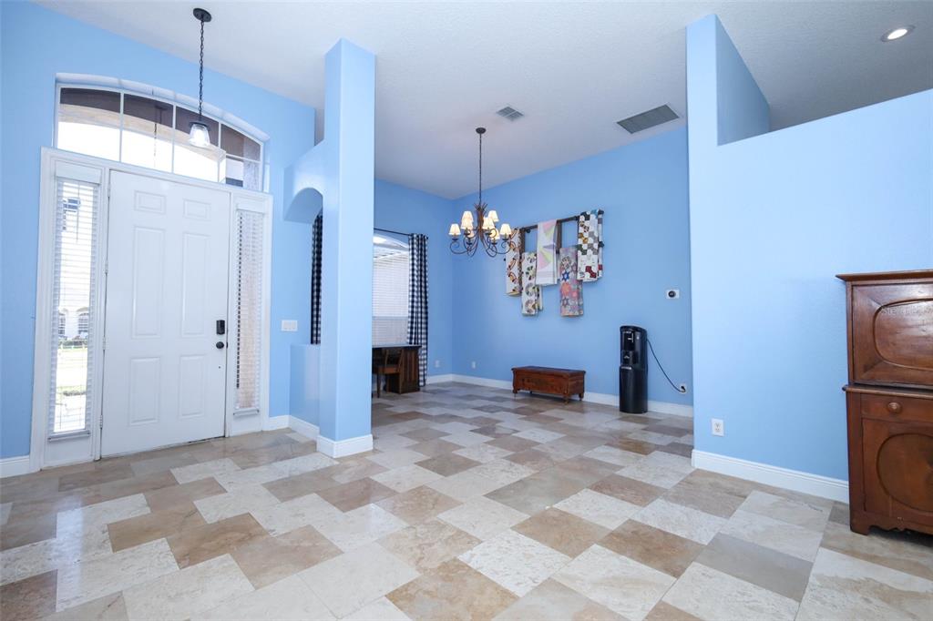 A bright blue entryway features a checkered tile floor, a chandelier, and a front door — 1620 PARKGLEN CIRCLE, APOPKA, FL