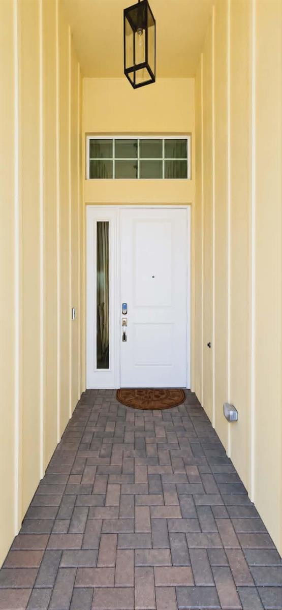 A white front door with a side window and transom sits at the end of a covered entryway — 19179 Rolling Acres Road, Loxahatchee FL 33470, LOXAHATCHEE, FL