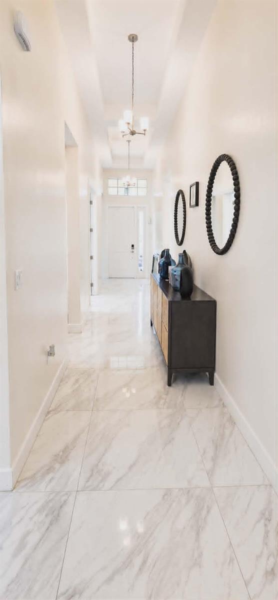 A bright hallway features white marble tile flooring, a dark wood console table, and mirrors — 19179 Rolling Acres Road, Loxahatchee FL 33470, LOXAHATCHEE, FL