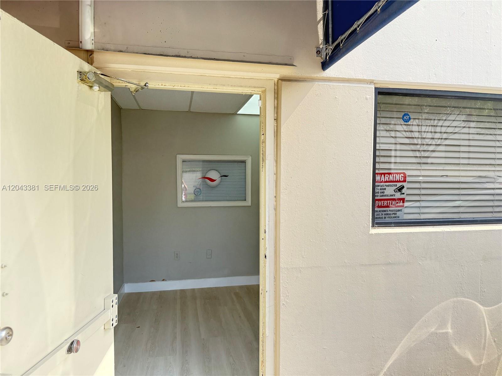 An open doorway leads into a small, empty office space with light-colored wood flooring — 2630 NW 112th Ave # 2630, Doral FL 33172, DORAL, FL