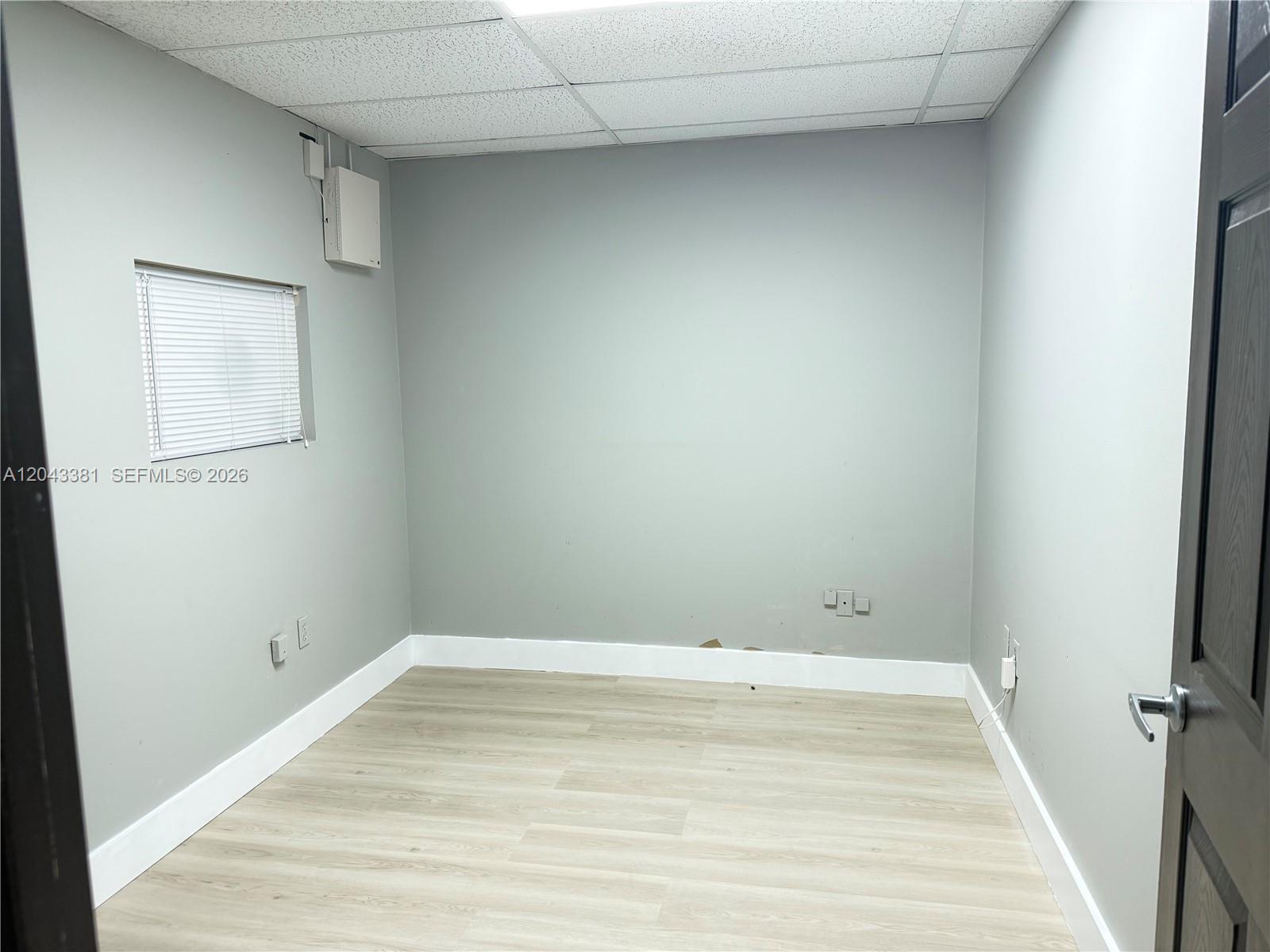 A small, empty office room features gray walls, light wood-look flooring, and a drop ceiling — 2630 NW 112th Ave # 2630, Doral FL 33172, DORAL, FL