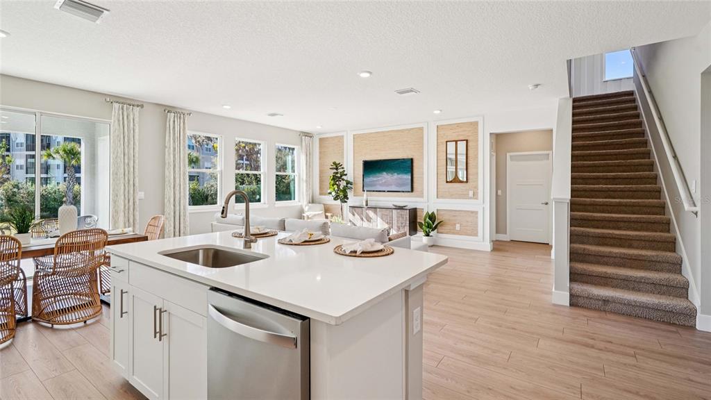 A kitchen island with a sink sits before a living area with stairs and wood flooring — 4249 SW 52ND LANE ROAD, OCALA, FL