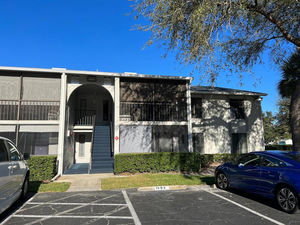 A two-story apartment building exterior features a covered staircase, screened balconies, and a parking lot — 1324 S PINE RIDGE CIRCLE UNIT D2, SANFORD, FL