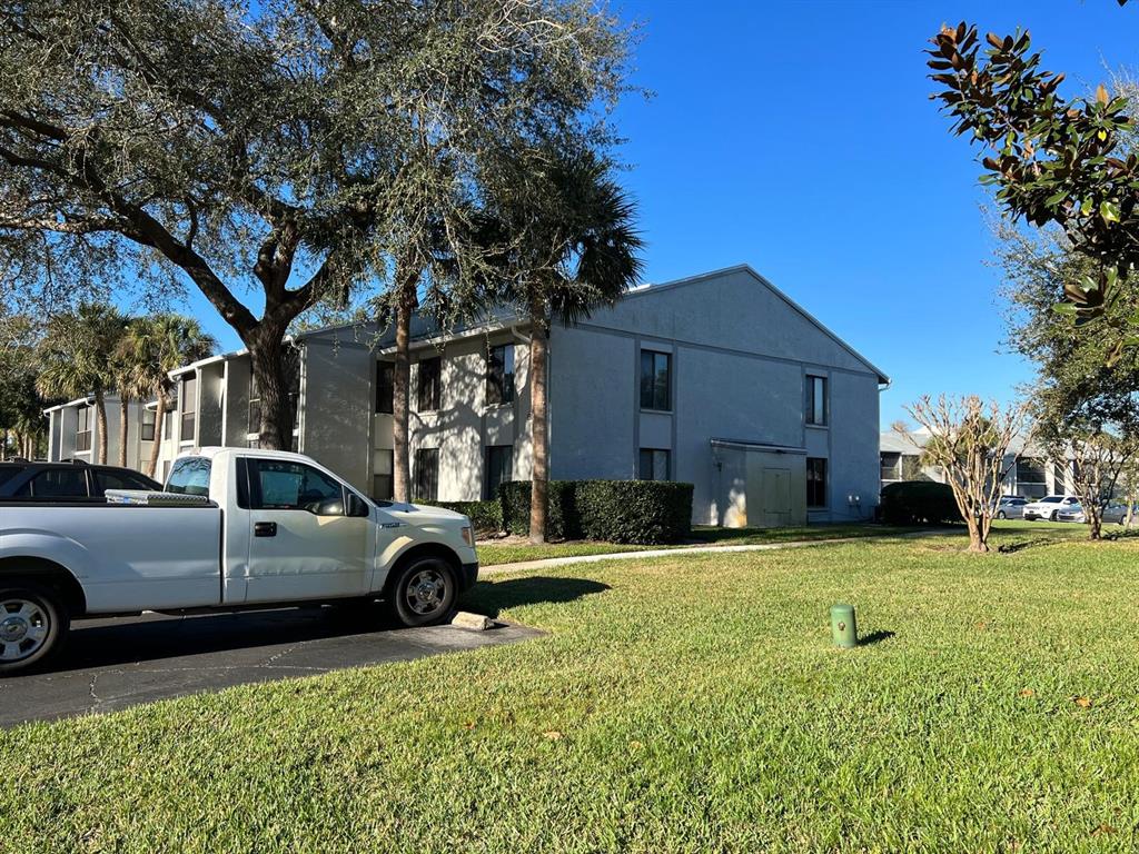 A white pickup truck is parked on asphalt in front of a multi-story apartment building — 1324 S PINE RIDGE CIRCLE UNIT D2, SANFORD, FL