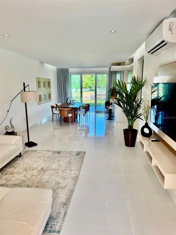 A modern living room features white tile floors, a dining area, and a large television — A1 Harbour Lakes A1 HARBOUR LAKES PALMAS DR UNIT A1, HUMACAO, PR