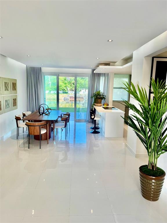 A bright, open-concept dining and kitchen area features white tile floors and a glass sliding door — A1 Harbour Lakes A1 HARBOUR LAKES PALMAS DR UNIT A1, HUMACAO, PR