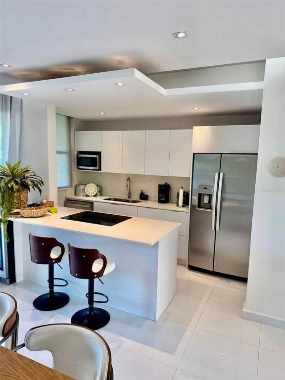 A modern kitchen features white cabinetry, stainless steel appliances, and a central island with seating — A1 Harbour Lakes A1 HARBOUR LAKES PALMAS DR UNIT A1, HUMACAO, PR